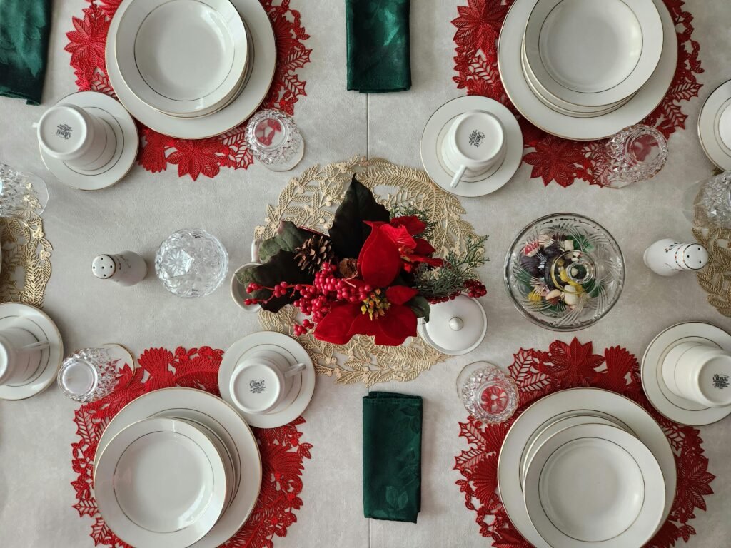 Top view of a beautifully set Christmas dinner table with porcelain plates and a vibrant floral centerpiece.